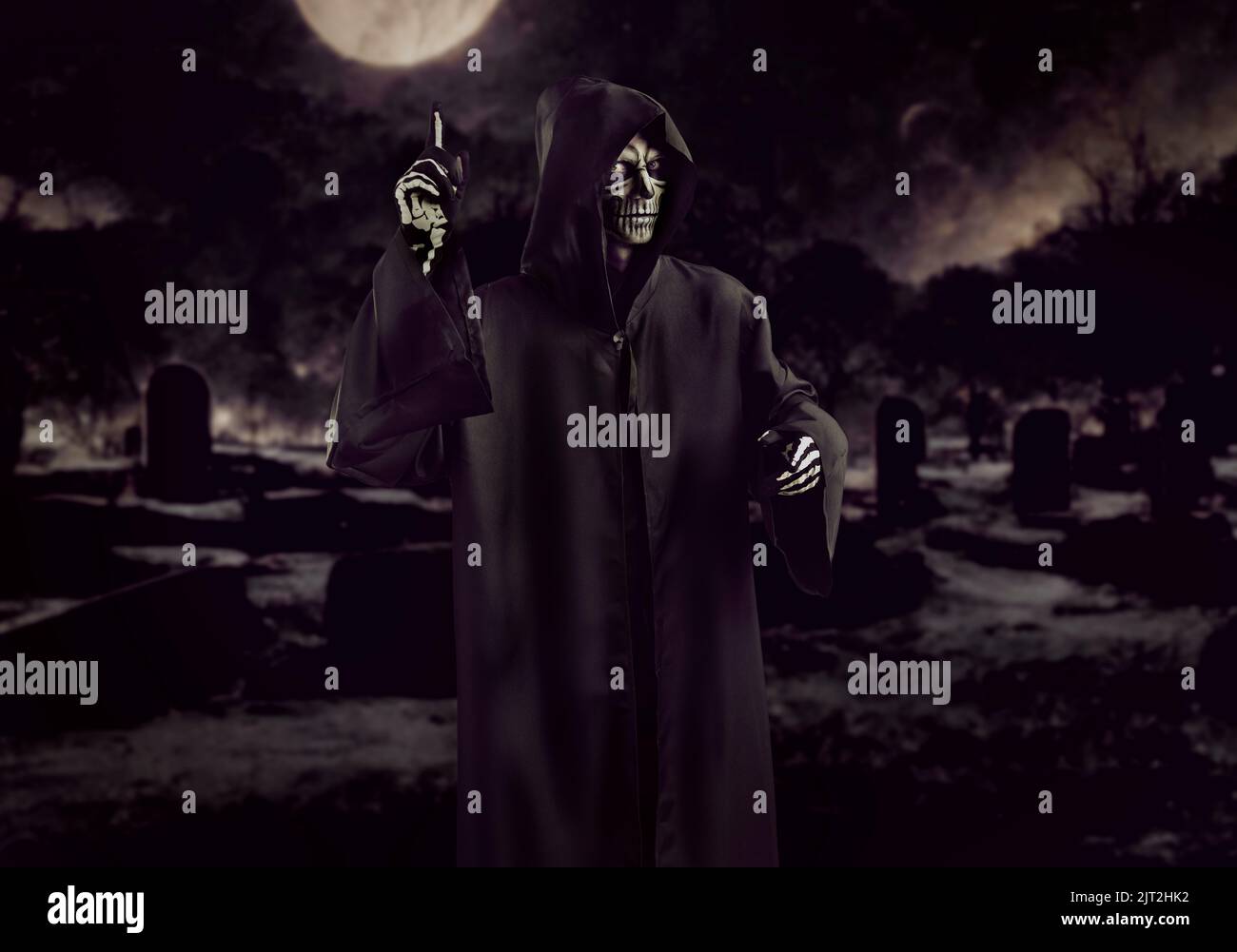 Mystisch gruselig grimmig reaper wirft Warnfinger auf schwarzen Friedhof Hintergrund. Stockfoto