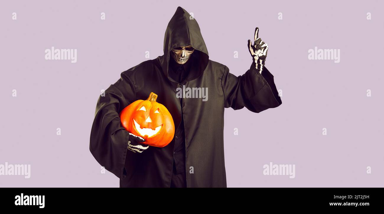 Mann im Bild von gruseligen Sensenmann mit Kürbis in der Hand hebt Finger in Warnung vor Idee. Stockfoto