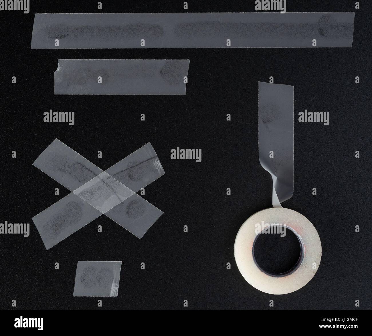 Verschiedene Stücke von Masking transparentem Band auf schwarzem Hintergrund isoliert Stockfoto