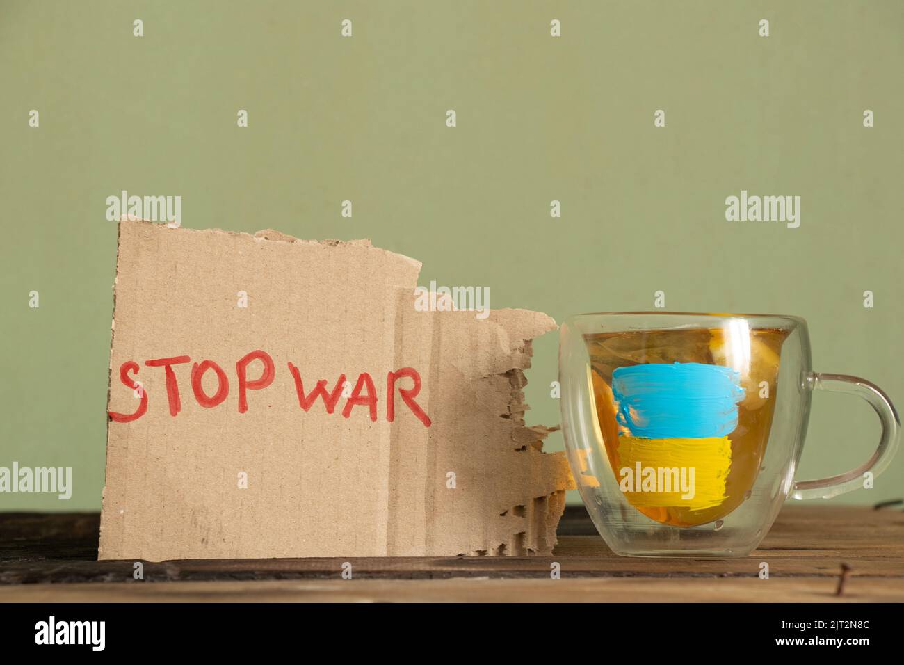 Schriftlicher Text Stopp Krieg in der Nähe von Cup mit gezeichneter Flagge der Ukraine, Protestaktion, kein Krieg zwischen Russland und der Ukraine. Pokal und Flagge der Ukraine zu Hause Stockfoto