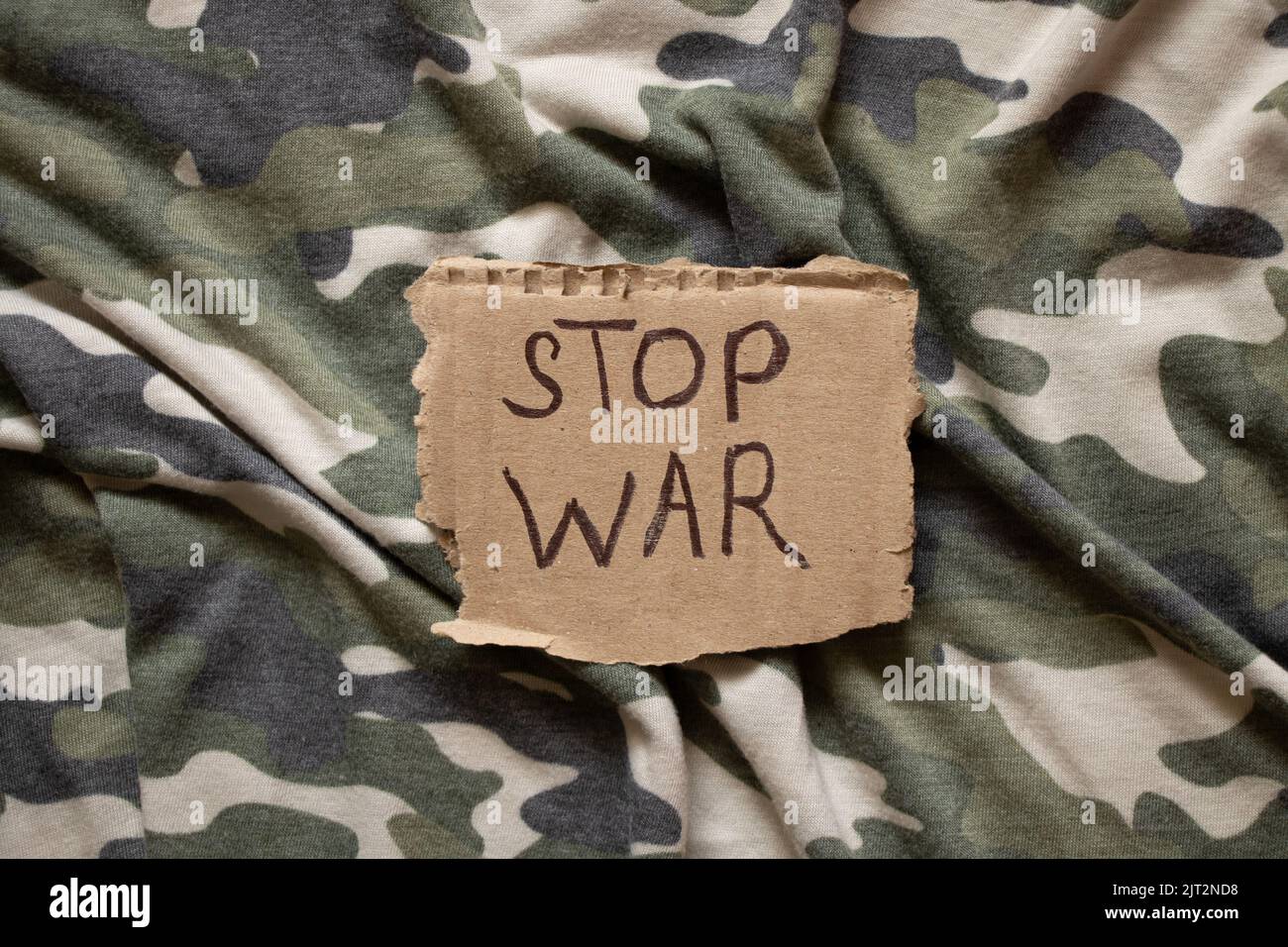 Stop war ist auf Papier geschrieben, das auf der Tarnuniform, Protestaktion, Militärkleidung des Soldaten liegt Stockfoto