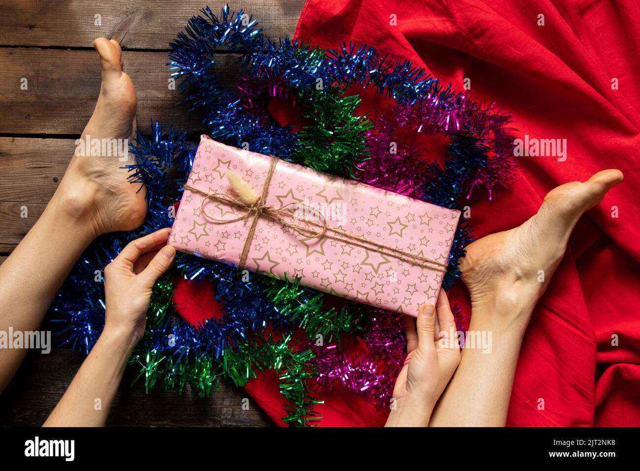 Mädchen entfaltet ein Geburtstagsgeschenk auf dem Holzboden des Hauses, Urlaub, ein Geschenk zu geben Stockfoto
