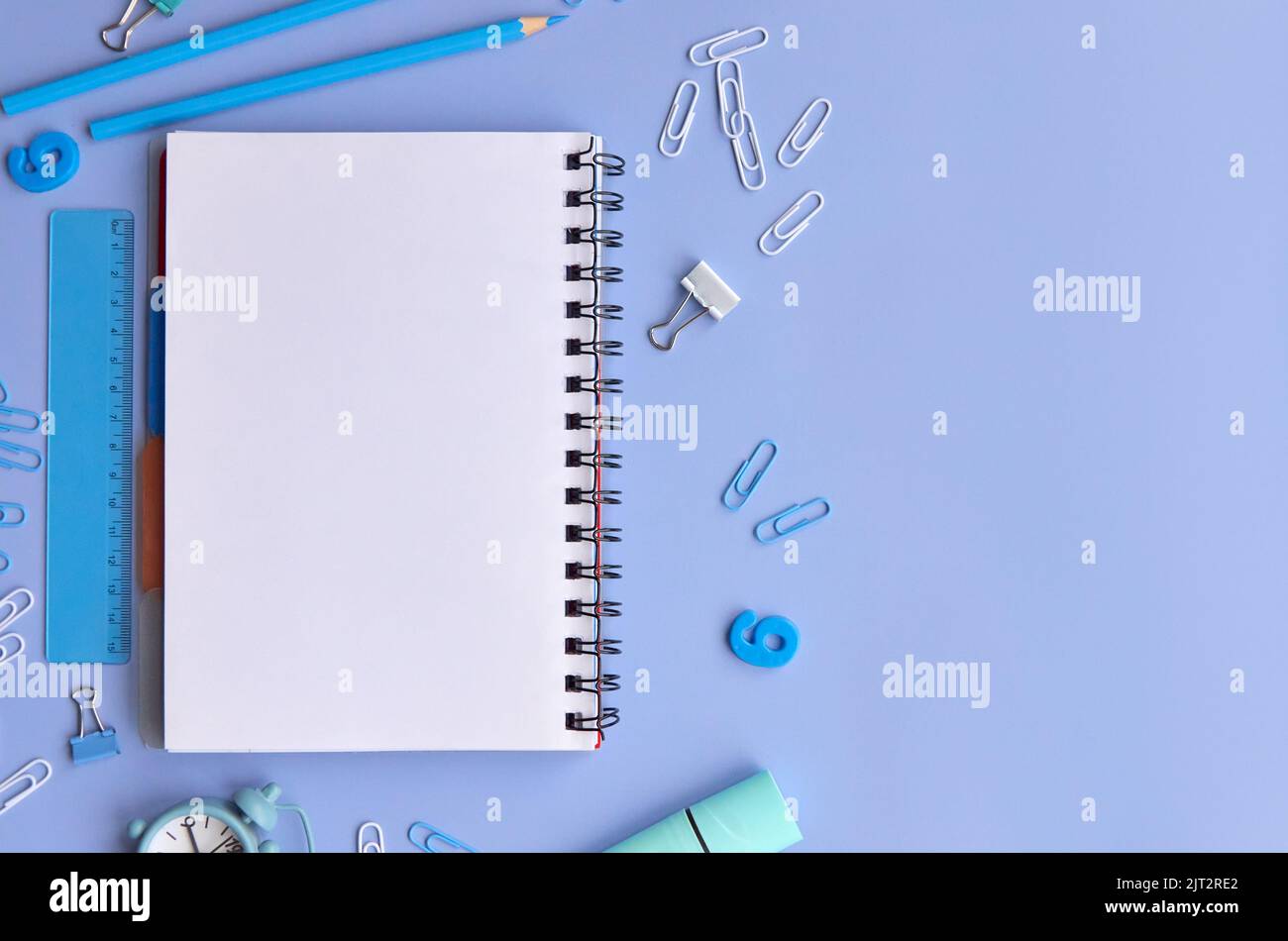 Schulpapiere und Notizbuch auf pastellfarbenem Lavendelhintergrund, senkrechtes Flatlay. Stockfoto