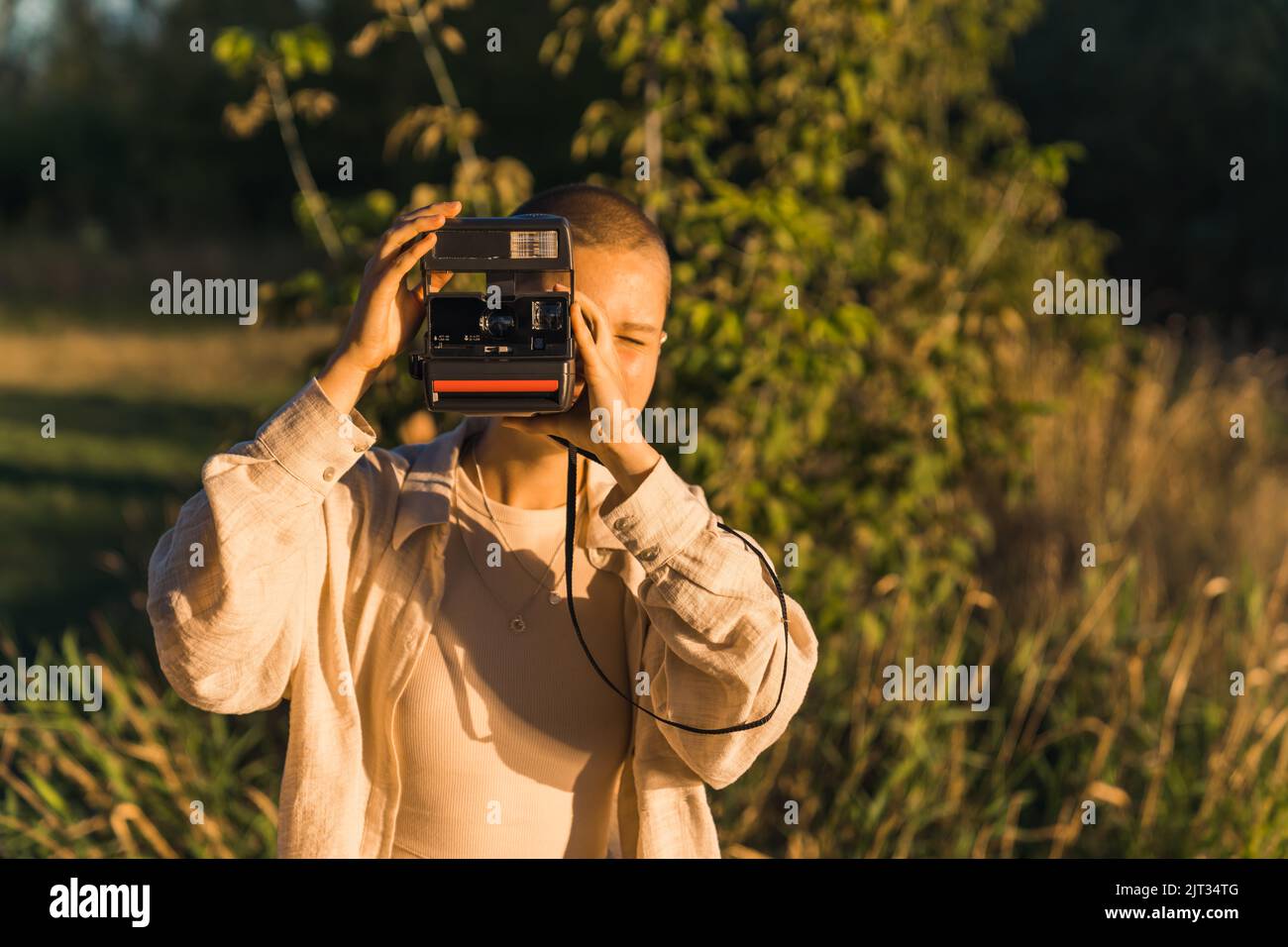Ein junges kaukasisches modernes Mädchen, das mit einer einstufigen polaroid-Spritzkamera Fotos von der beeindruckenden Aussicht einfangen kann. Naturliebhaber genießen den Sonnenuntergang im Sommer. Hochwertige Fotos Stockfoto