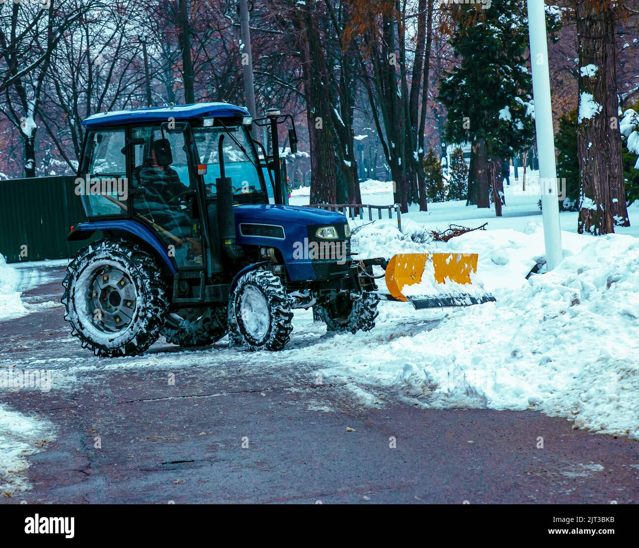 Blauer Traktor reinigt Stadtstraßen und Straßen nach starkem Schneefall. Kommunale Dienste sind an der Schneeräumung beteiligt. Stockfoto