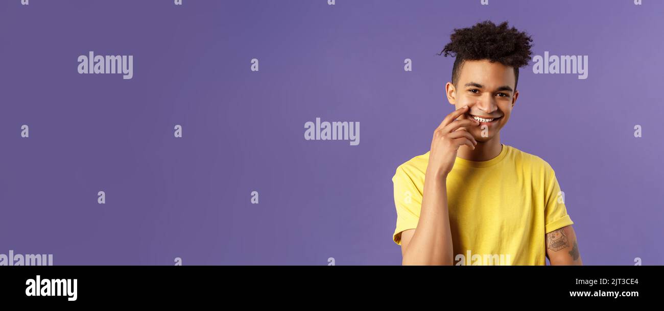 Nahaufnahme des netten jungen hispanischen Schwulen Mannes mit Dreads, Tätowierungen, berührender Lippe sinnlich und flirrrrrend lächelnd, jemand wirklich süß auscheckend Stockfoto