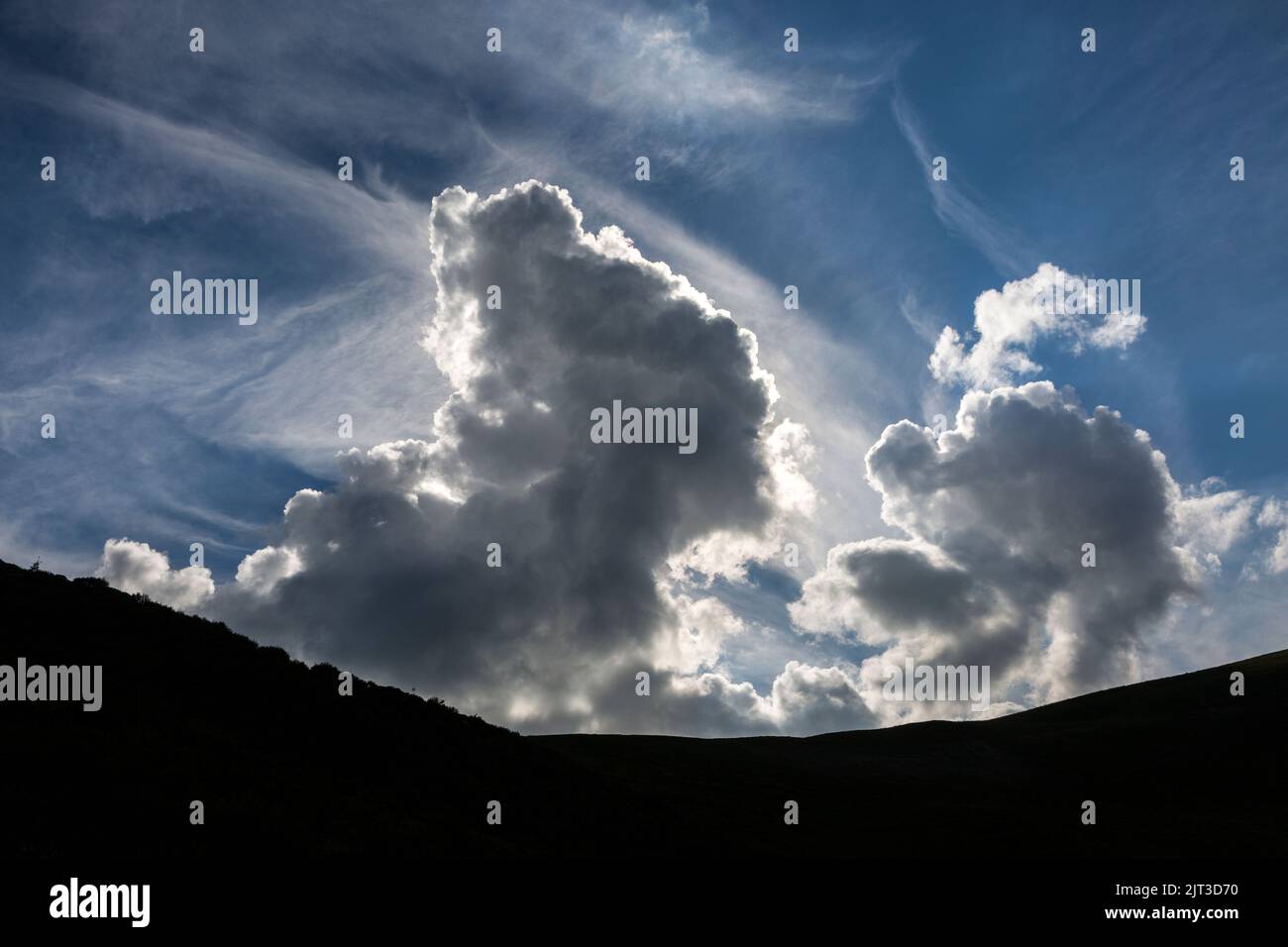 Riesige dramatische Wolken in den Bergen vor Sonnenuntergang. Cumulus Wolken auf dem Hintergrund des blauen Himmels Stockfoto