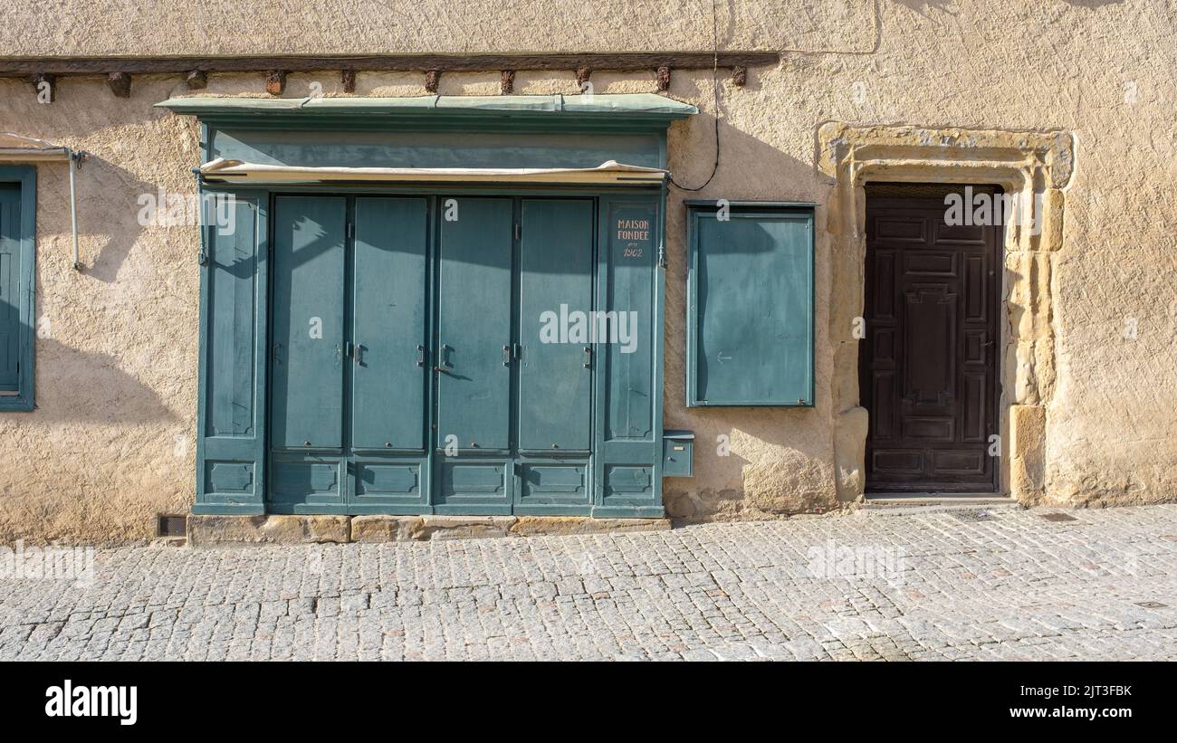 Ein geschlossener Laden in einem Steingebäude mit blauen Fensterläden in einem südfranzösischen Dorf Stockfoto