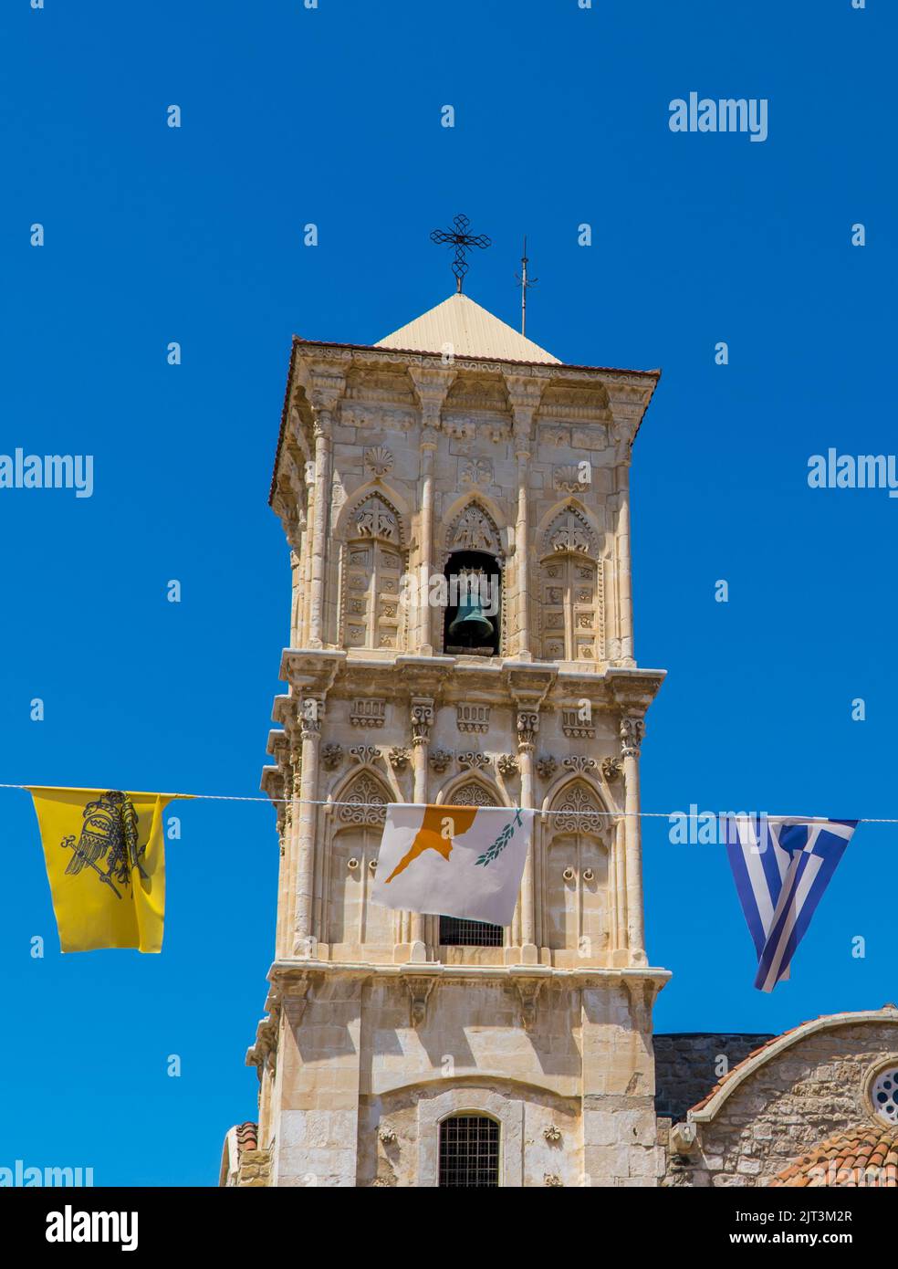 Eine vertikale Aufnahme von griechischen und zypriotischen Flaggen vor der St. Lazarus Kirche in Larnaca, Zypern Stockfoto