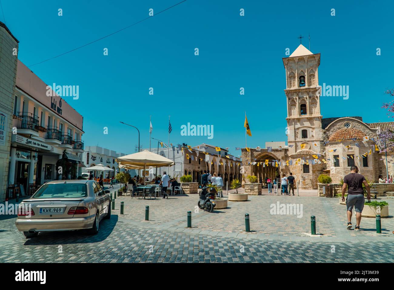 Eine wunderschöne Aufnahme von Menschen, die an einem sonnigen Tag in der St. Lazarus Kirche Larnaca, Zypern, draußen spazieren Stockfoto