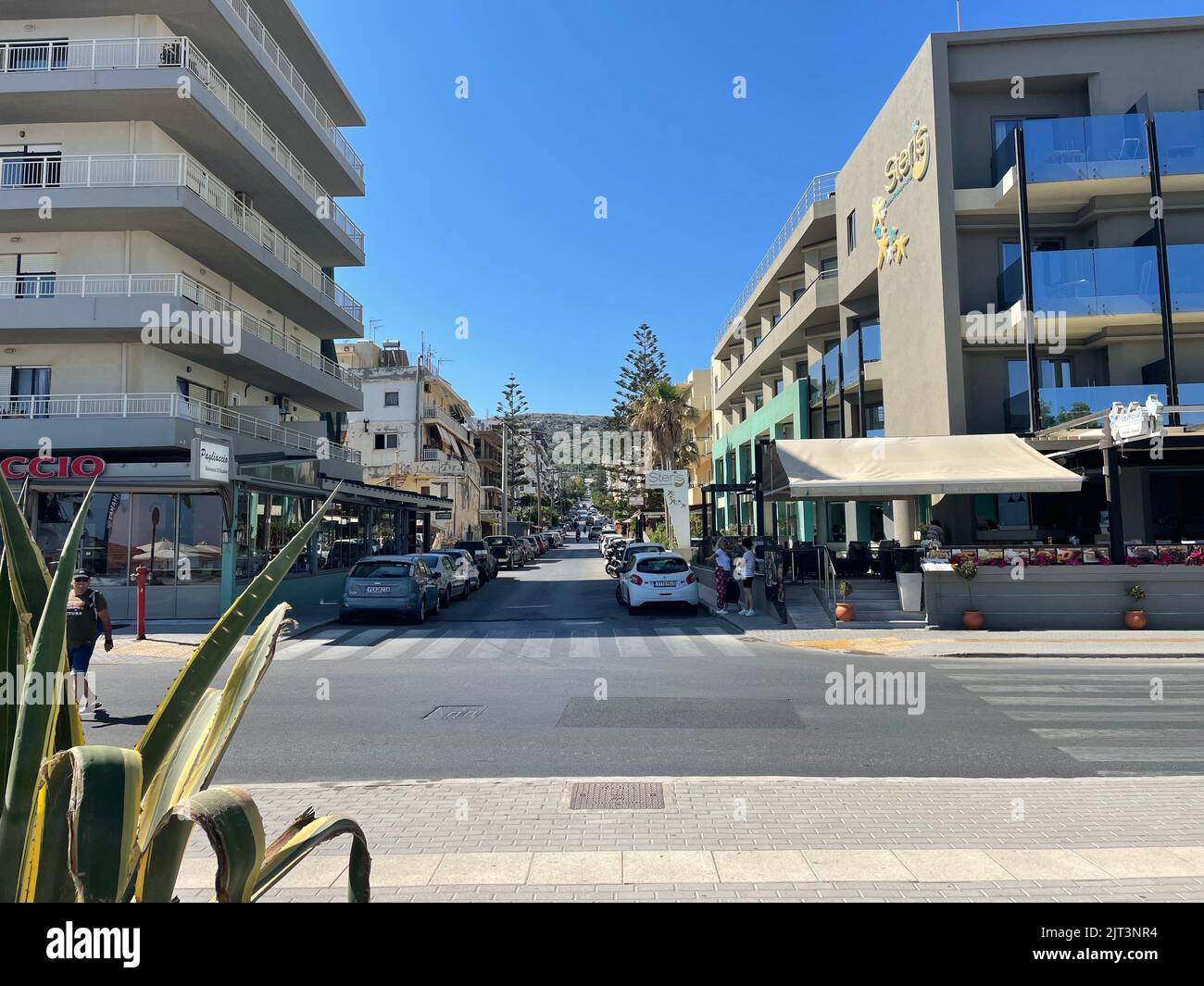 Ein schöner Blick auf die Straßen von Rethymno auf Kreta, Griechenland an einem sonnigen Morgen mit geparkten Autos um Gebäude Stockfoto