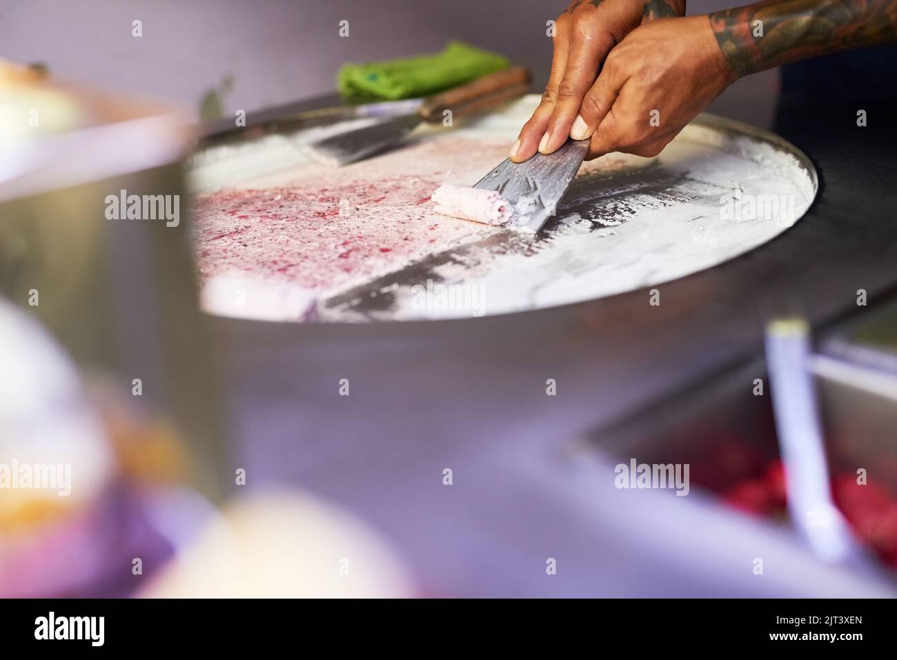 Ihre Geschmacksknospen werden überrascht sein. Ein nicht identifizierbarer Lebensmittelhändler bereitet an einem Marktstand ein süßes Leckerbissen zu. Stockfoto