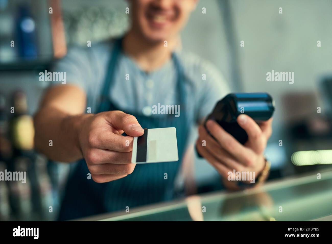 Deine Karte... ein nicht erkennbarer Barista, der eine Kreditkartenzahlung abnimmt. Stockfoto