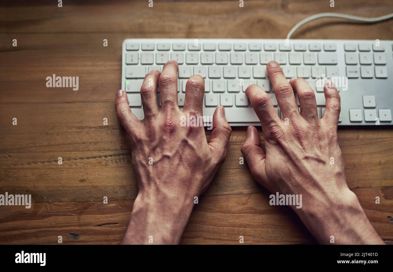 Lassen Sie seine Finger reden. High-Angle-Aufnahme eines nicht identifizierbaren Mannes, der nachts auf einer Computertastatur tippt. Stockfoto