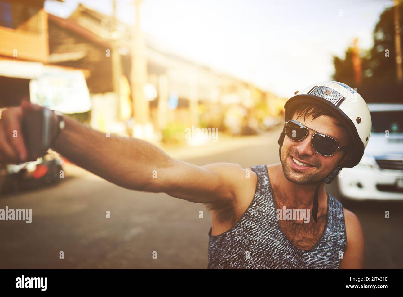 Halten Sie jeden Moment fest, den Sie festhalten sollten. Ein junger Mann nimmt ein Selfie auf, während er auf seinem Roller unterwegs ist. Stockfoto