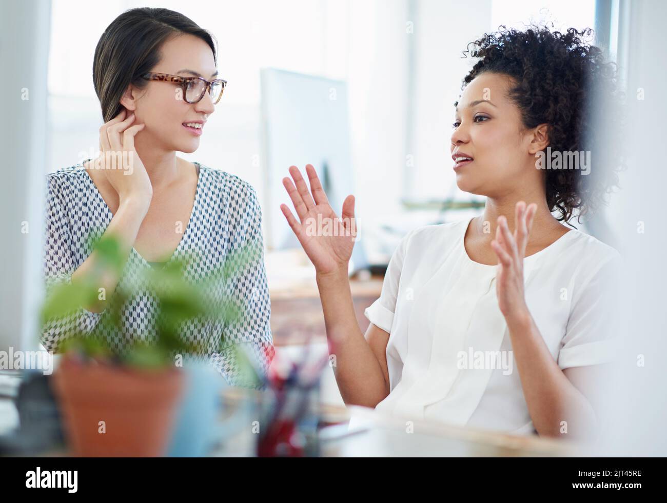 Zusammenarbeit an einem Design. Zwei junge Designerinnen diskutieren im Büro über die Arbeit. Stockfoto