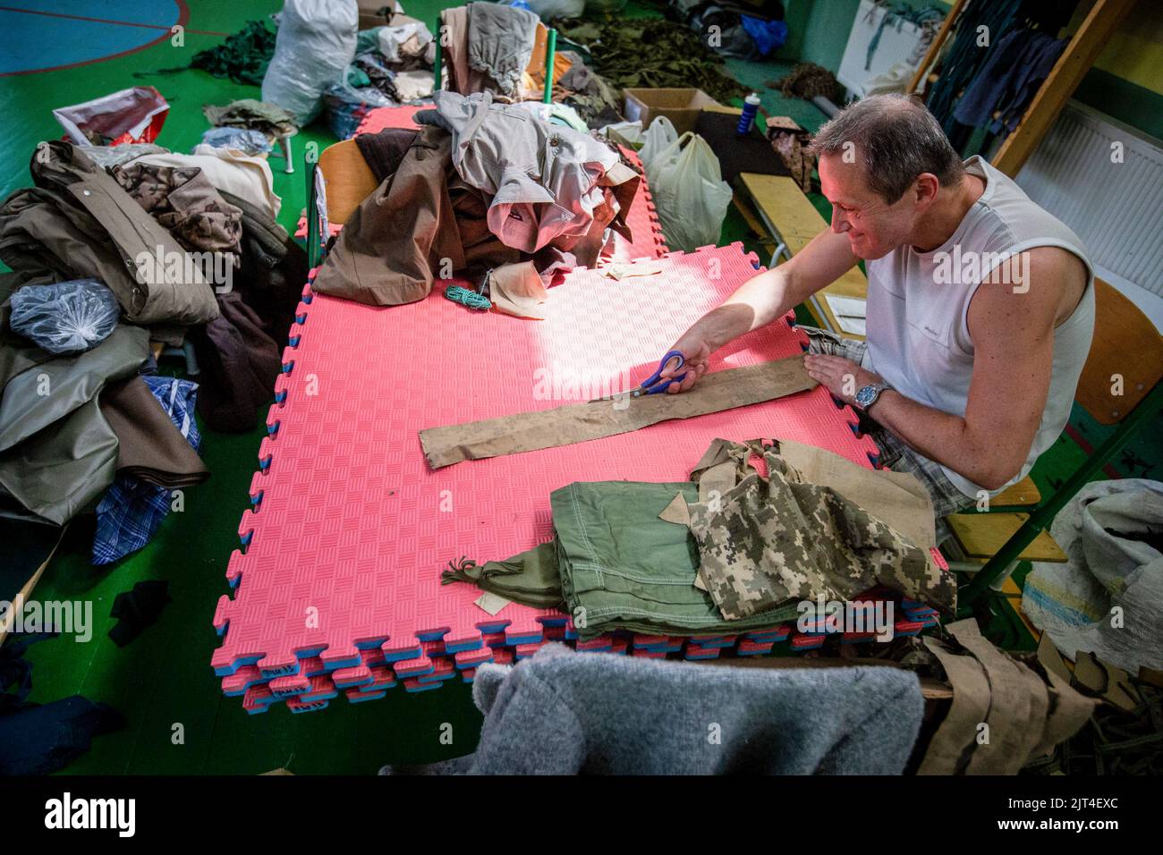 Ein Freiwilliger stellt in einer Schulhalle in Kiew Stoffrohlinge zum Weben von Tarnnetzen für die ukrainische Armee her. Am 24. Februar marschierten 2022 russische Truppen in das ukrainische Territorium ein und begannen einen Konflikt, der Zerstörung und eine humanitäre Krise provoziert hat. Stockfoto