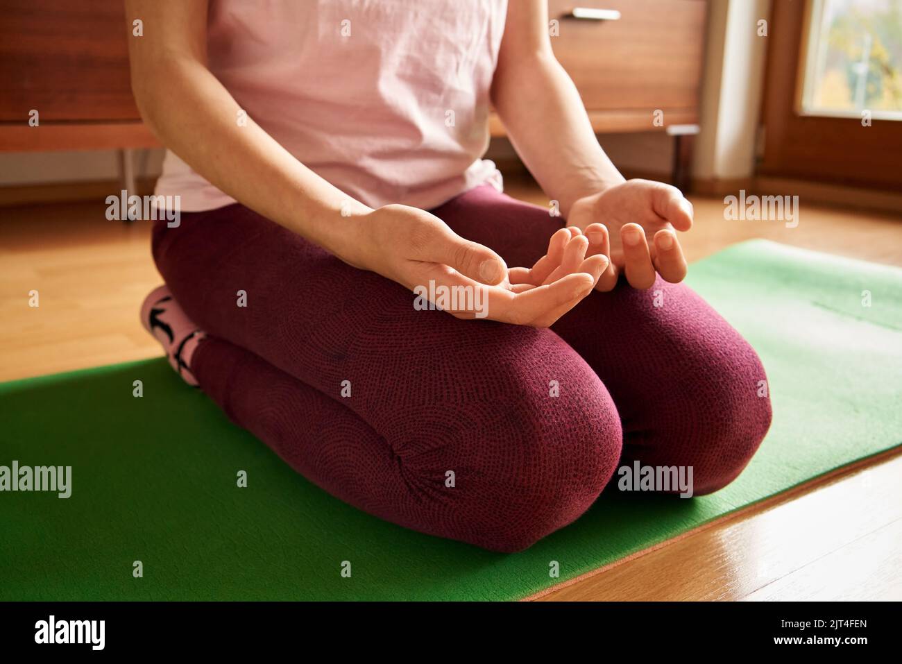 Teenager-Mädchen kniet und praktiziert Yoga oder eine Entspannungsübung zu Hause Stockfoto