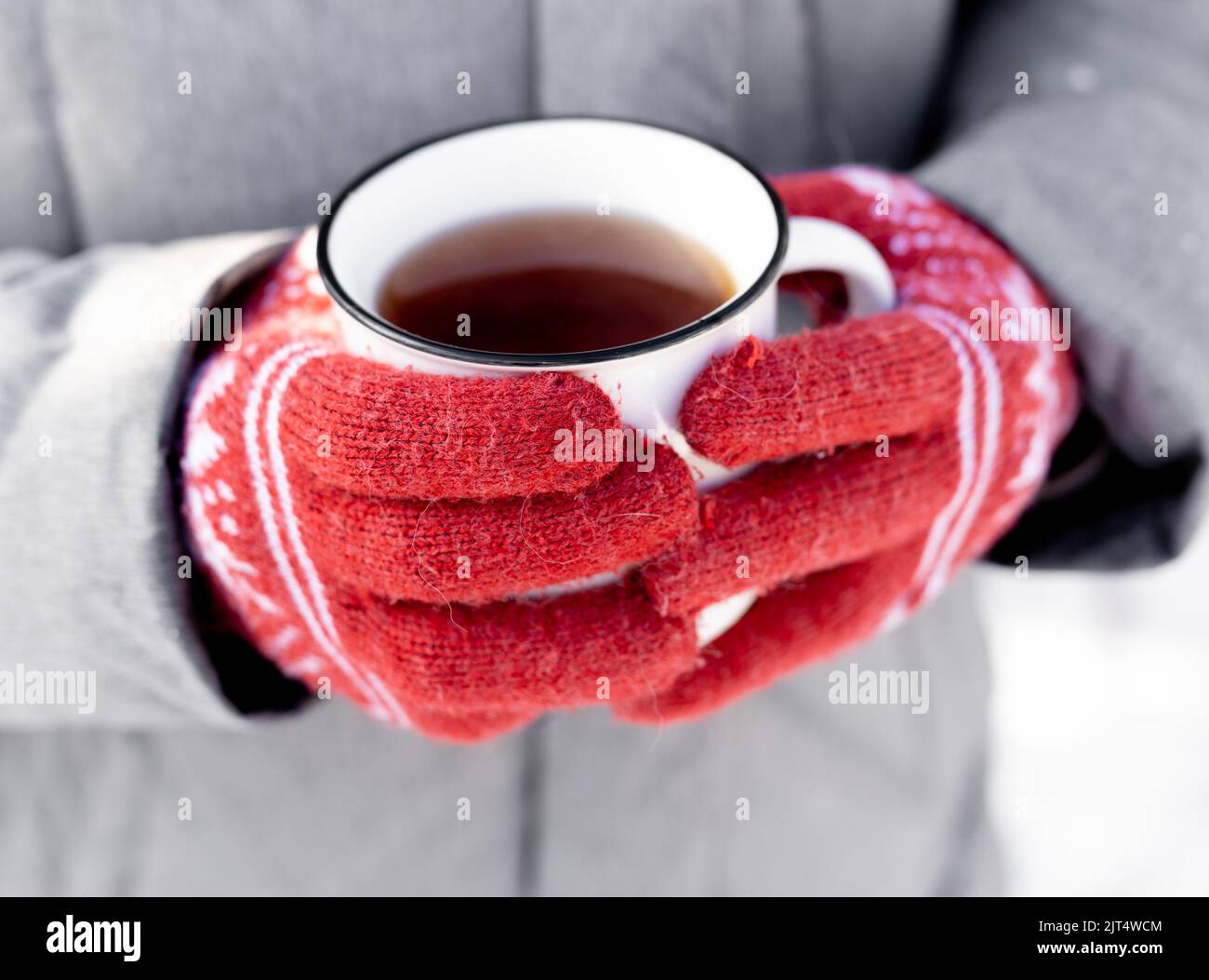 Hände in Handschuhen, die den Becher halten Stockfoto