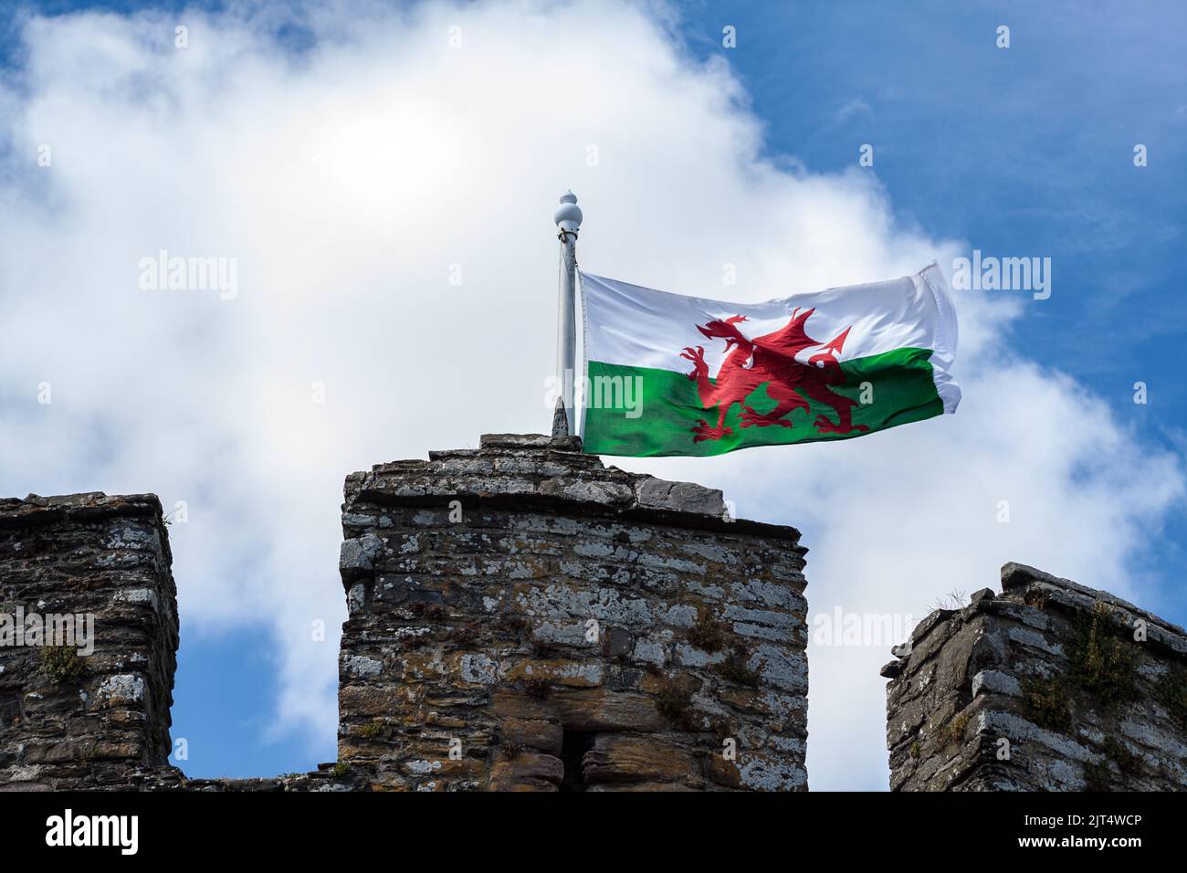 Die walisische Flagge, die über der Spitze eines walisischen Schlosses fliegt. Stockfoto