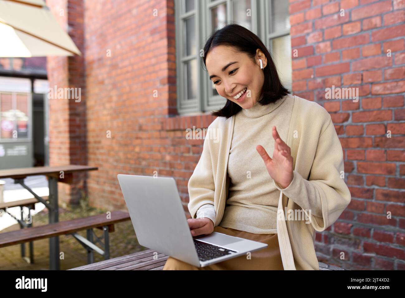 Junge asiatische Frau mit Laptop-Videoanrufe mit virtuellen Treffen im Freien. Stockfoto