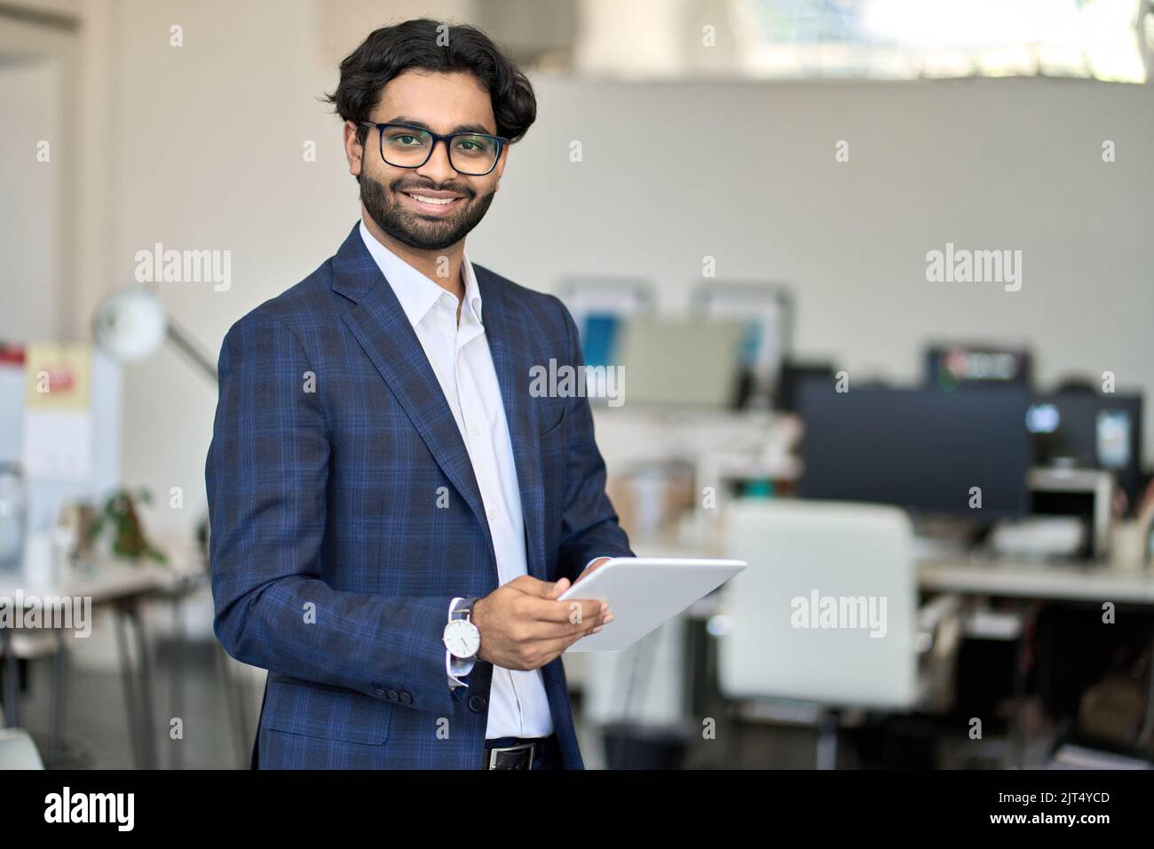 Lächelnder junger indischer männlicher Manager in Anzug mit Tablet, Porträt. Stockfoto