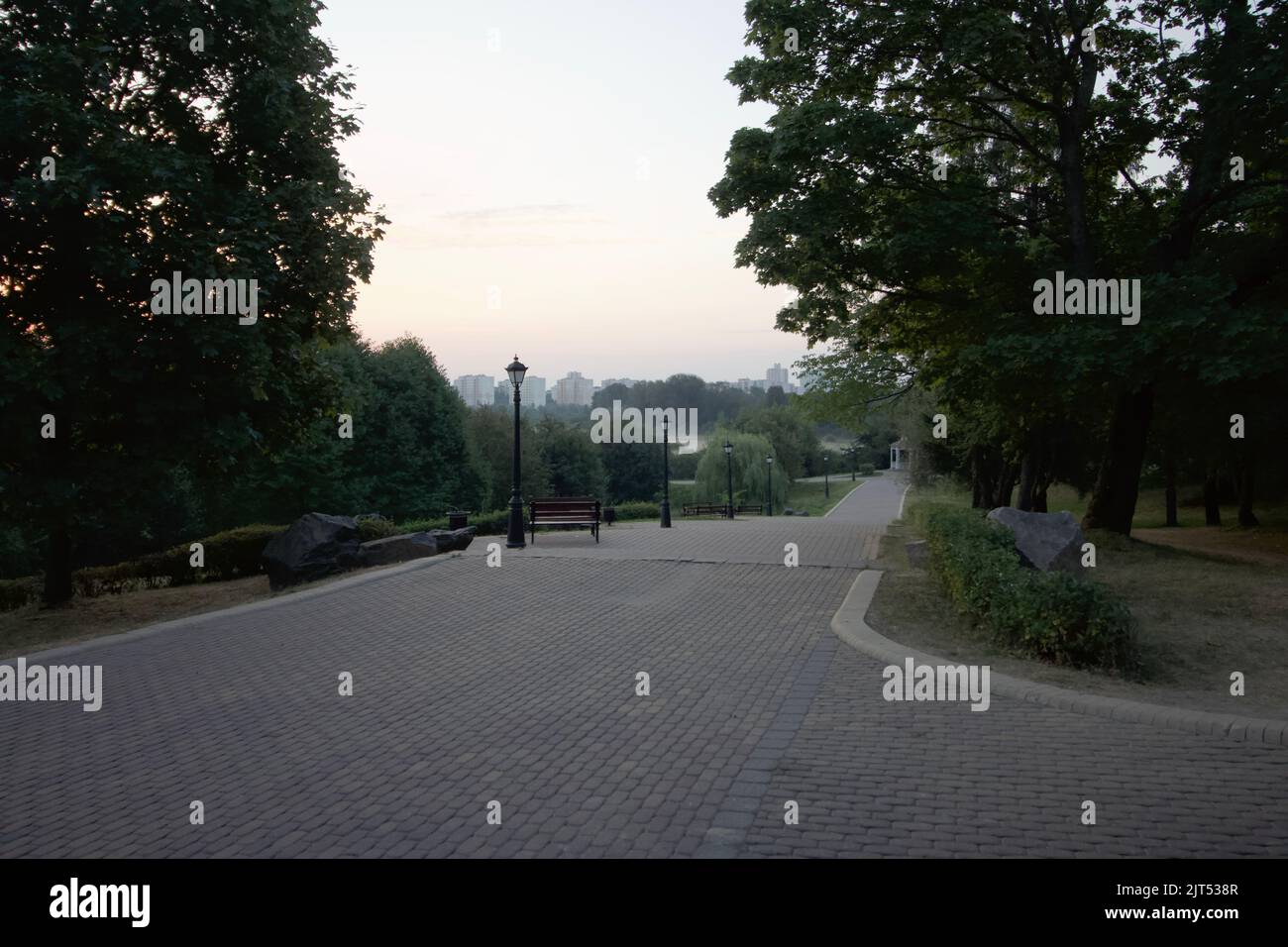 Fußgängerwege im Stadtpark. Vintage Bänke und Laternen. Stadtpark im Morgengrauen. Stockfoto