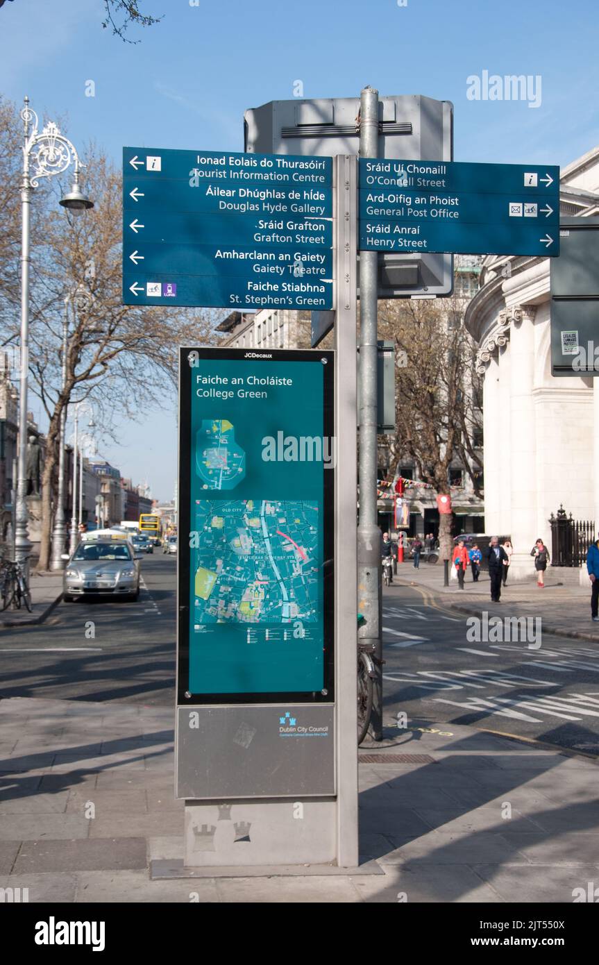 Straßenblick mit Touristenschild, Dublin, Eire. Zweisprachiges Schild mit Wegbeschreibung zu einigen der wichtigsten Sehenswürdigkeiten in Dublin. Bank of Ireland. Stockfoto