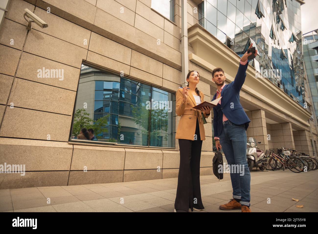 Ein Geschäftsmann steht vor dem Gebäude und zeigt, wo sein Kollege hinsehen muss Stockfoto