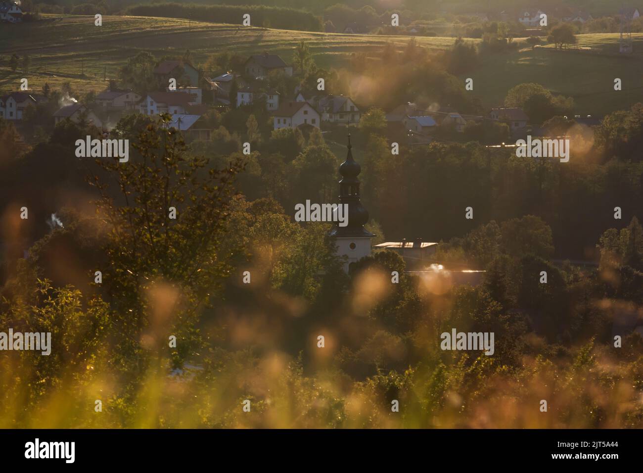 Ländliche Landschaft, Kirche und Häuser zwischen Bäumen und Feldern, Herbstlandschaft bei Sonnenuntergang, Natur Herbst Hintergrund Stockfoto