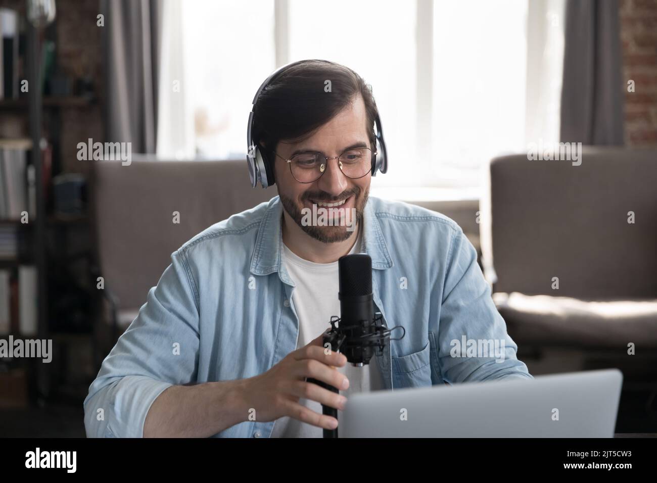 Glücklich engagiert Radio-Host, Blogger Mann in drahtlosen Kopfhörern Stockfoto