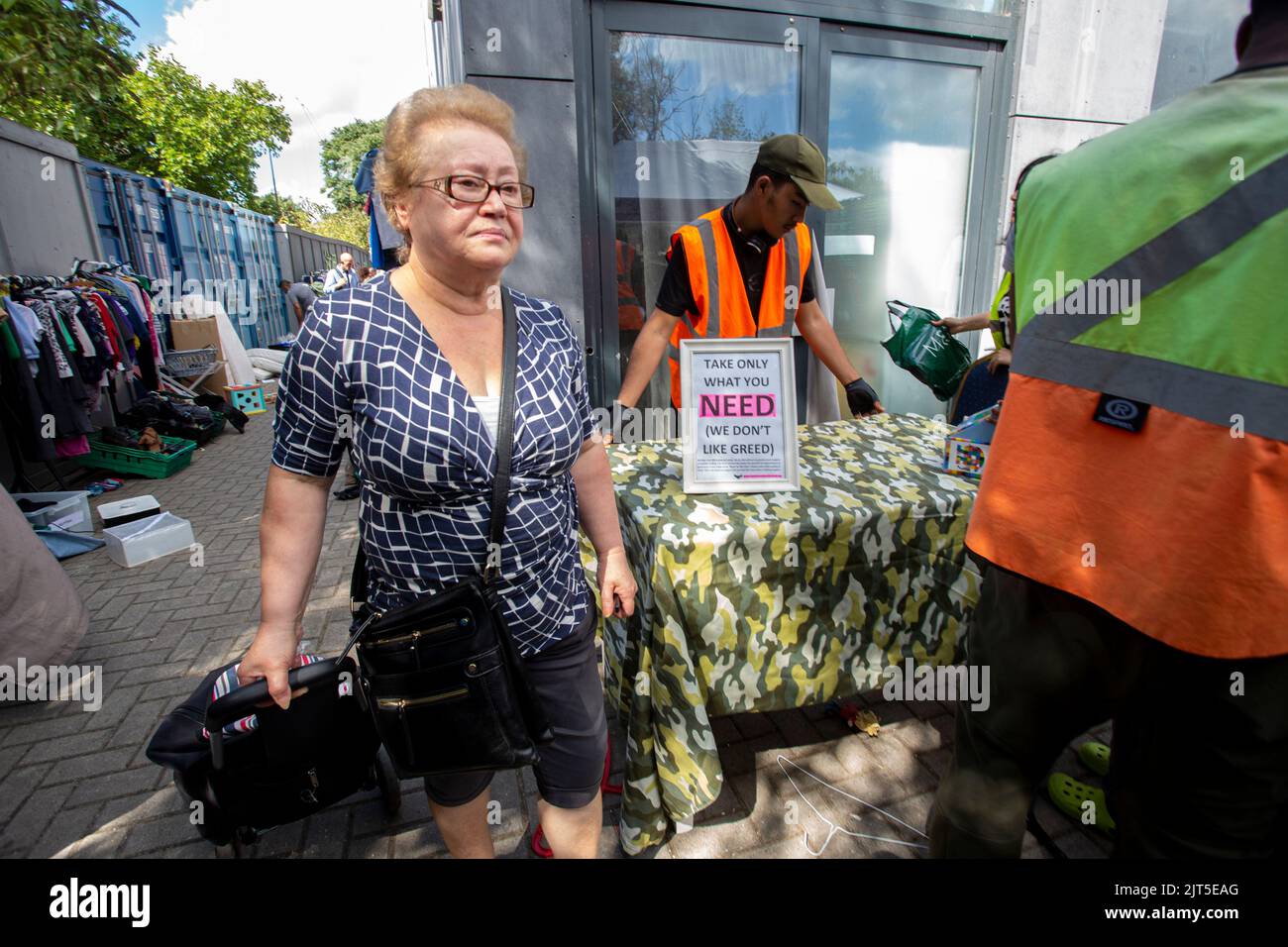 Ältere Frau auf der Suche nach Kleidung im Lewisham Donation Hub in London, England Stockfoto