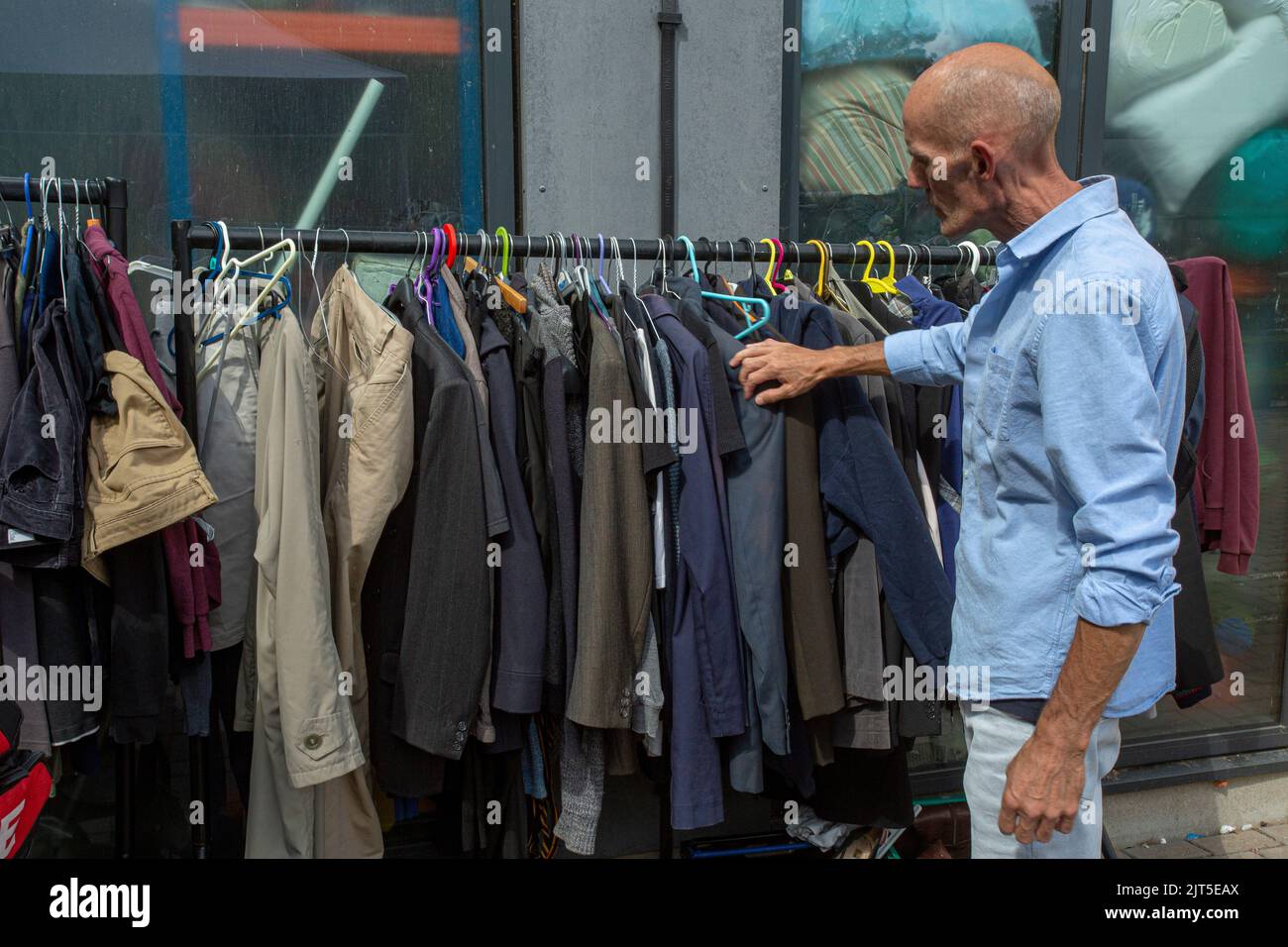 Weißer britischer Mann auf der Suche nach Kleidung im Lewisham Donation Hub in London, England Stockfoto