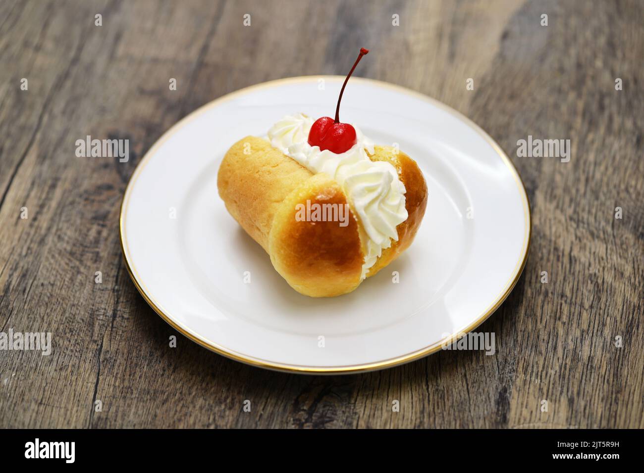 Rum baba ( baba au Rhum ) mit Schlagsahne dekoriert; traditionelles französisches und italienisches Dessert Stockfoto