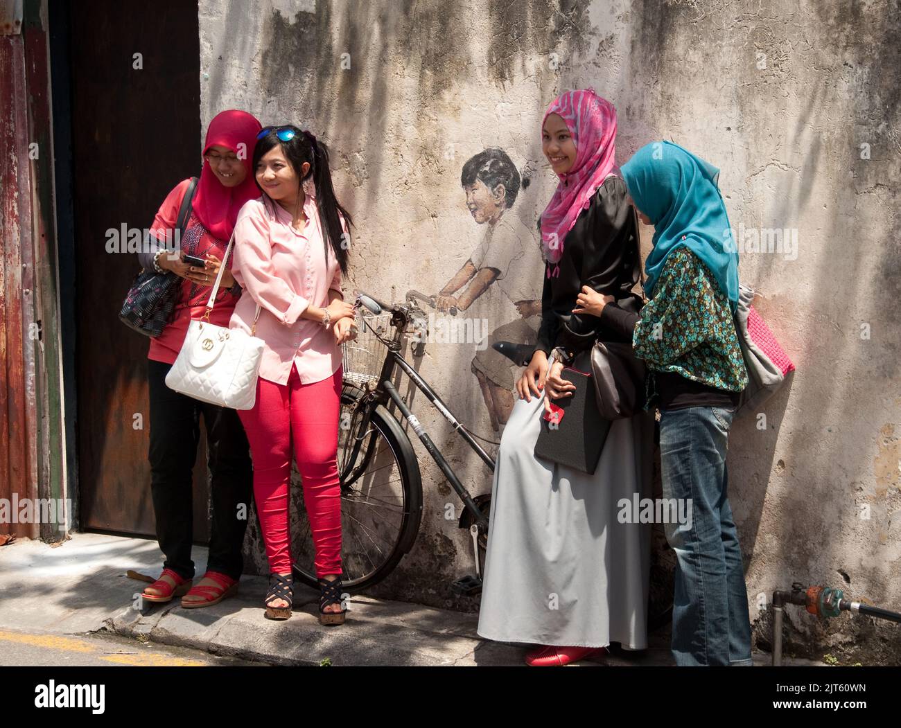 Posing around Street Art, George Town, Penang, Malaysia, Asia. Junge muslimische Frauen genießen sich und haben Spaß. Street Art ist sehr häufig in G Stockfoto