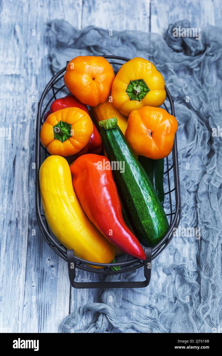 Rohe Zucchini und Paprika im Korb auf blauem Hintergrund Stockfoto