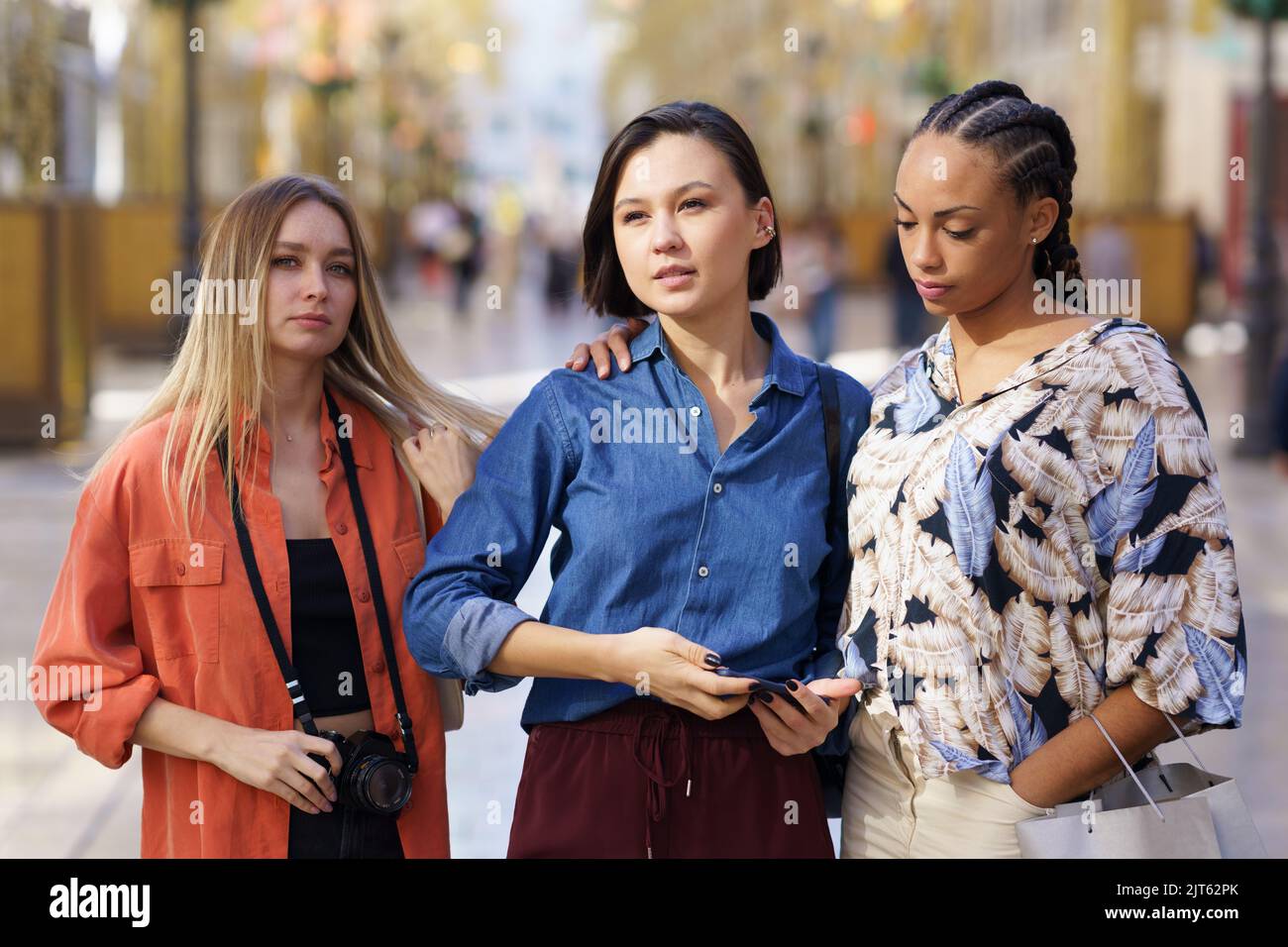 Trendige, vielfältige weibliche Touristen, die auf der Straße der Stadt im Sonnenlicht stehen Stockfoto