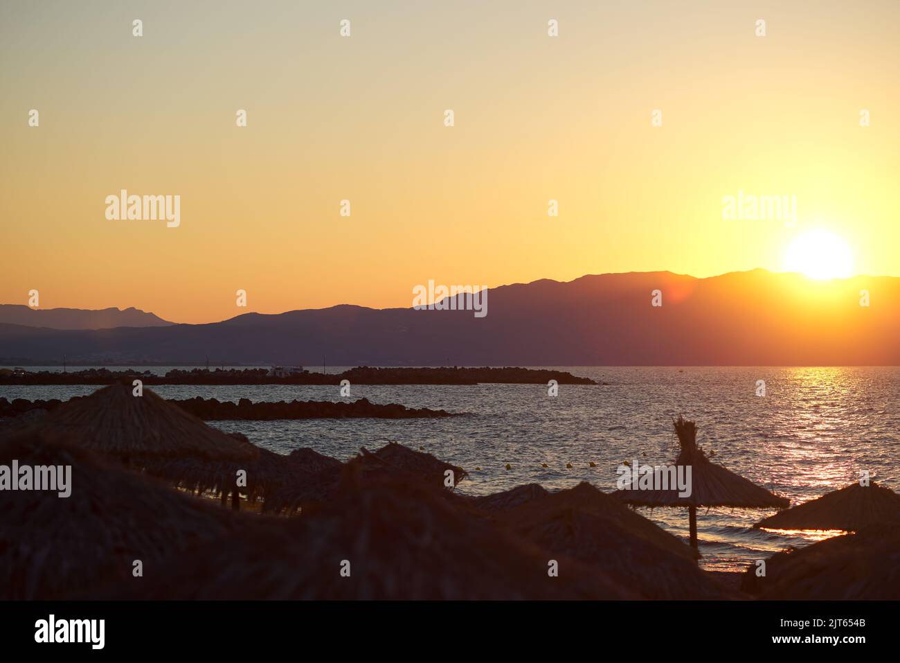 Sonnenschirme am Strand und am Meer bei Sonnenuntergang in Chania Kreta - Griechenland Stockfoto