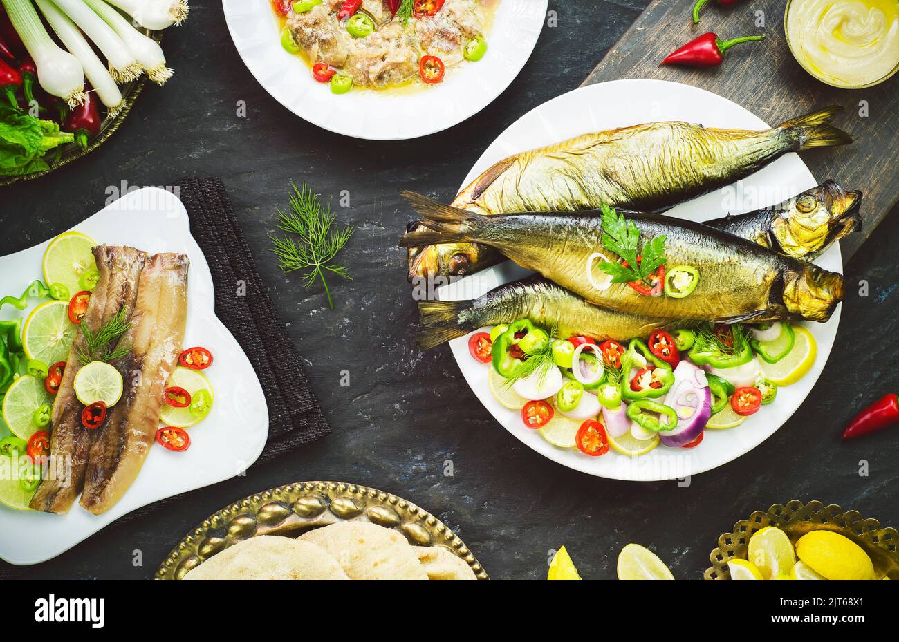 Mediterrane Küche, geräucherter Heringsfisch serviert mit grünen Zwiebeln, Zitrone, Chili, Salat, Gewürzen, Pita-Brot und Tahini-Sauce. Stockfoto