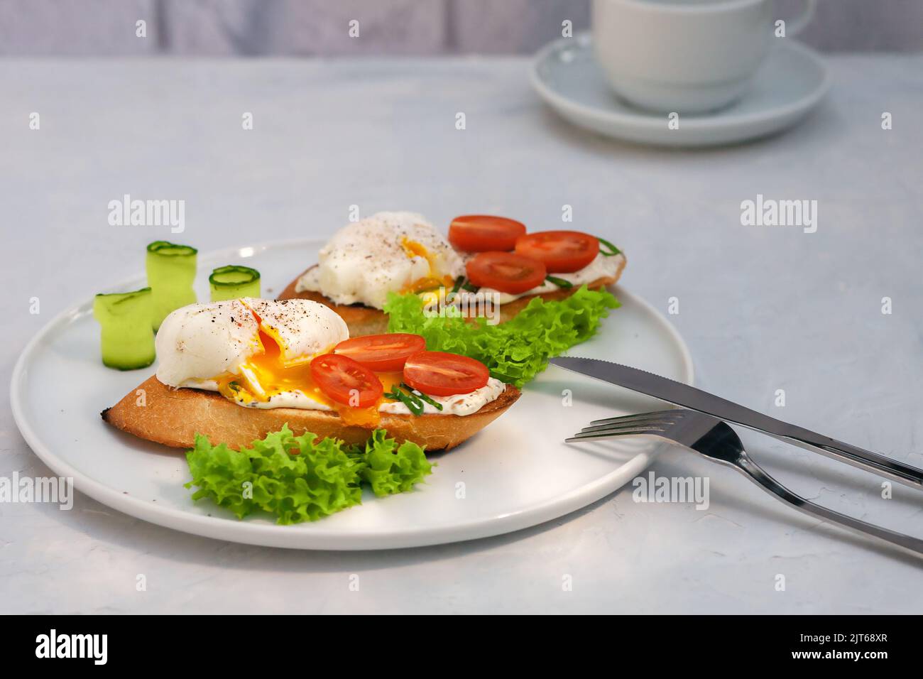 Pochiertes Eiertoast mit Tomaten und Frischkäse und Brot auf einem Teller. Gesundes Lebensmittelkonzept. Stockfoto