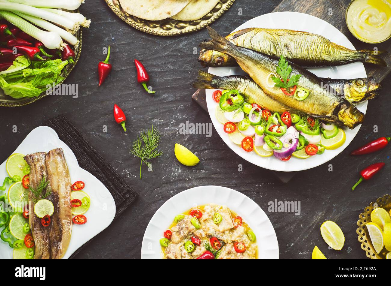 Mediterrane Küche, geräucherter Heringsfisch serviert mit grünen Zwiebeln, Zitrone, Chili, Salat, Gewürzen, Pita-Brot und Tahini-Sauce. Stockfoto