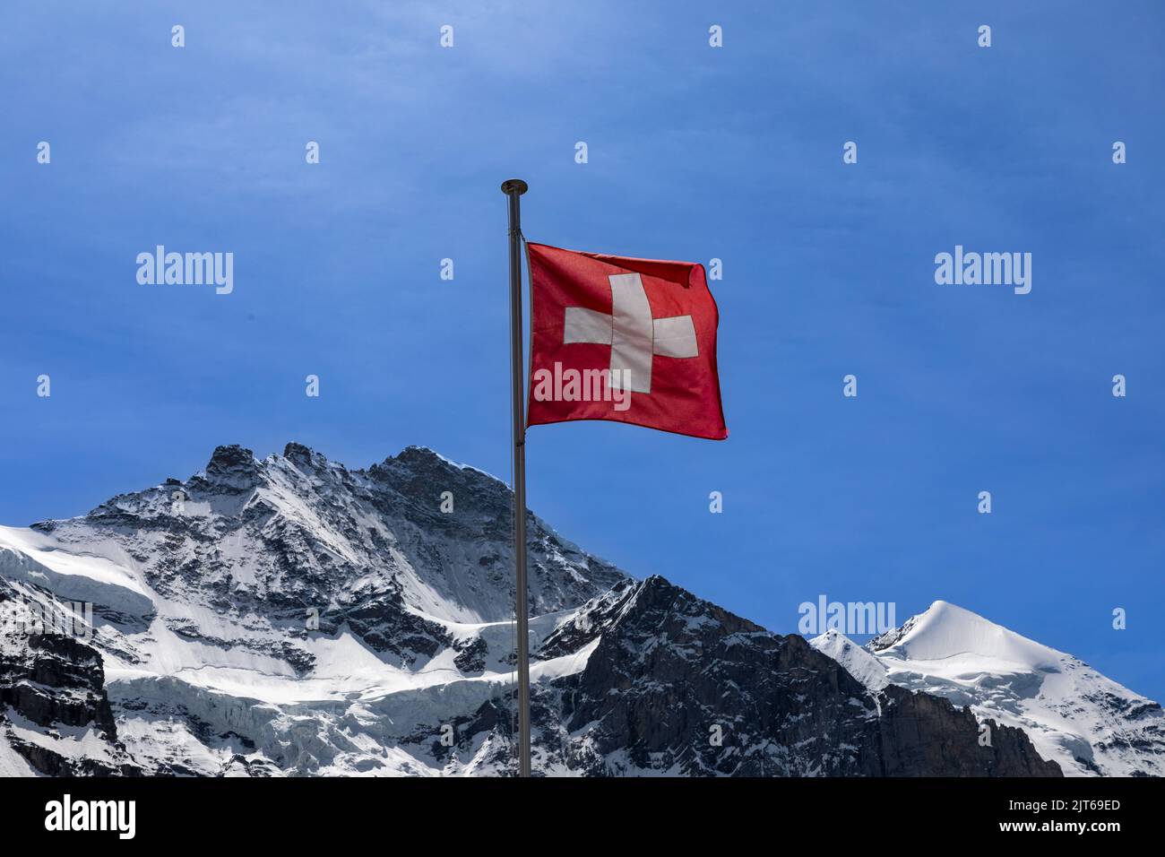 Flagge der Schweiz mit der Spitze der Jungfrau dahinter. Stockfoto