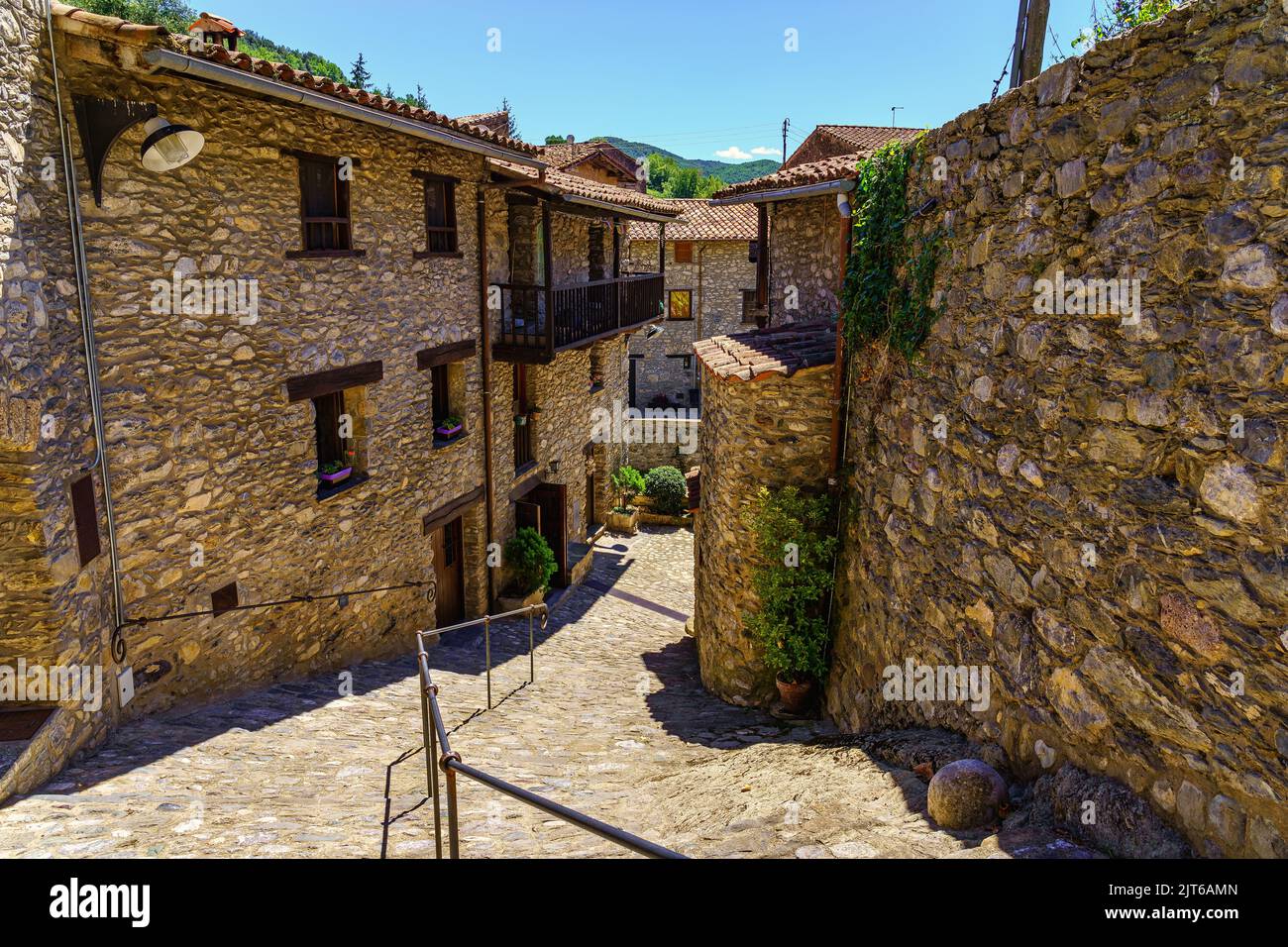 Schmale Gasse, die zum Fluss mit Häusern auf beiden Seiten aus Stein und Holz Balkone, beget, Katalonien absteigt. Stockfoto