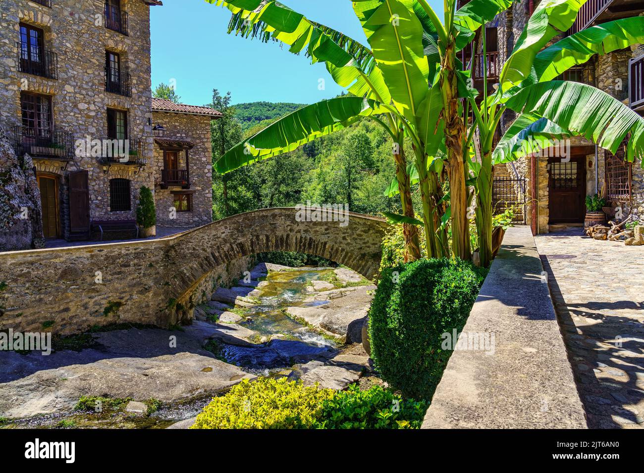 Brücke aus Stein und kleinem Bach, der durch das Bergdorf Beget, Girona, Spanien, führt. Stockfoto