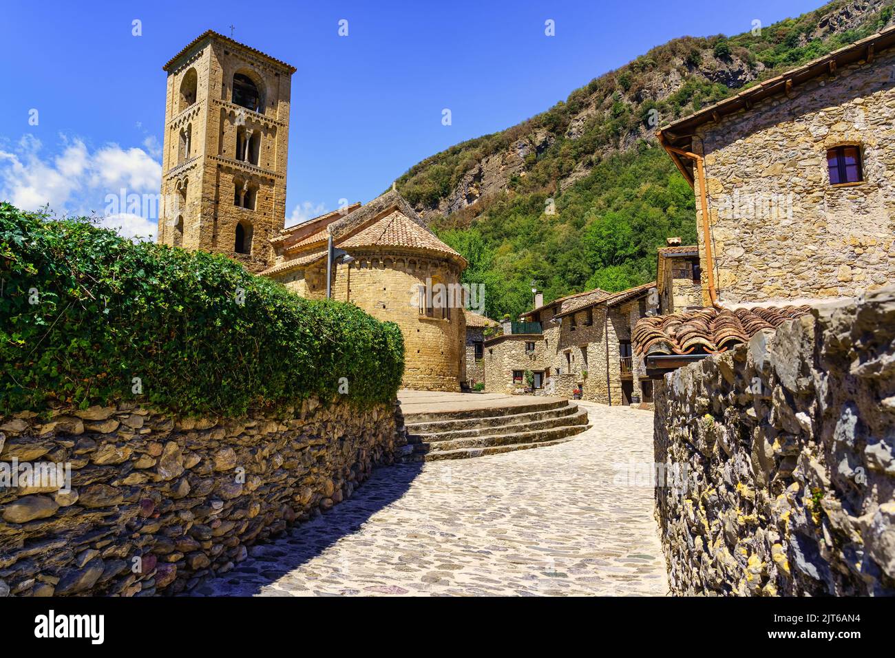 Enge Gasse aus Stein, die zum Stadtplatz führt, wo die Kirche ist, beget, Girona. Stockfoto