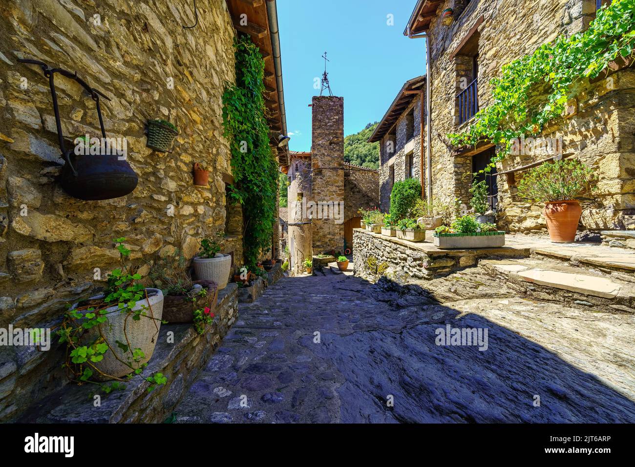 Malerische Gasse mit Häusern aus Stein und Töpfen mit Blumen im mittelalterlichen Dorf Beget, Girona, Katalonien. Stockfoto