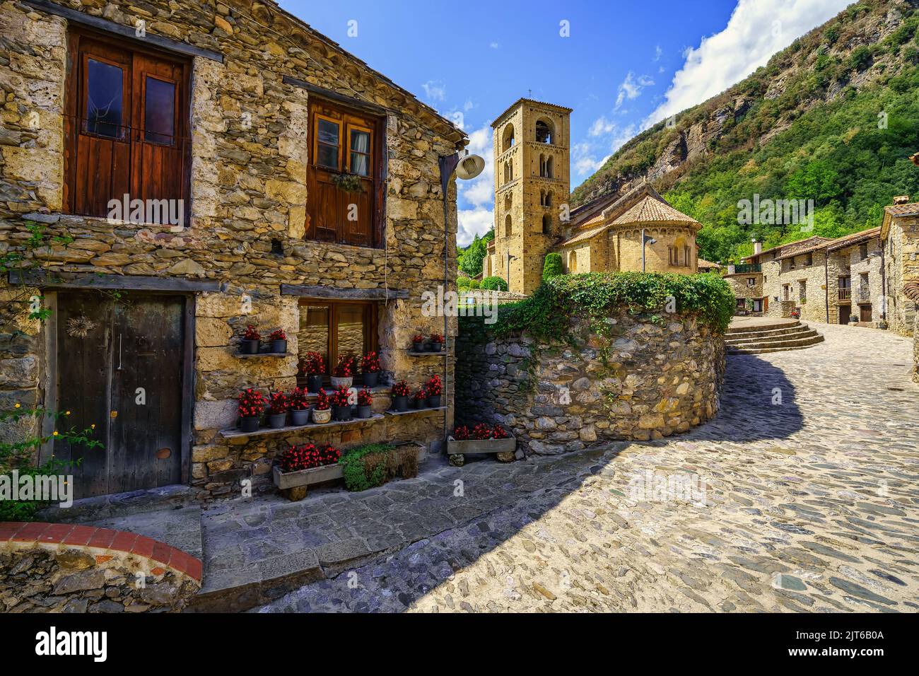 Malerische Gasse mit Häusern voller Blumen und Hauptplatz mit romanischer Kirche im Bergdorf Beget, Katalonien. Stockfoto