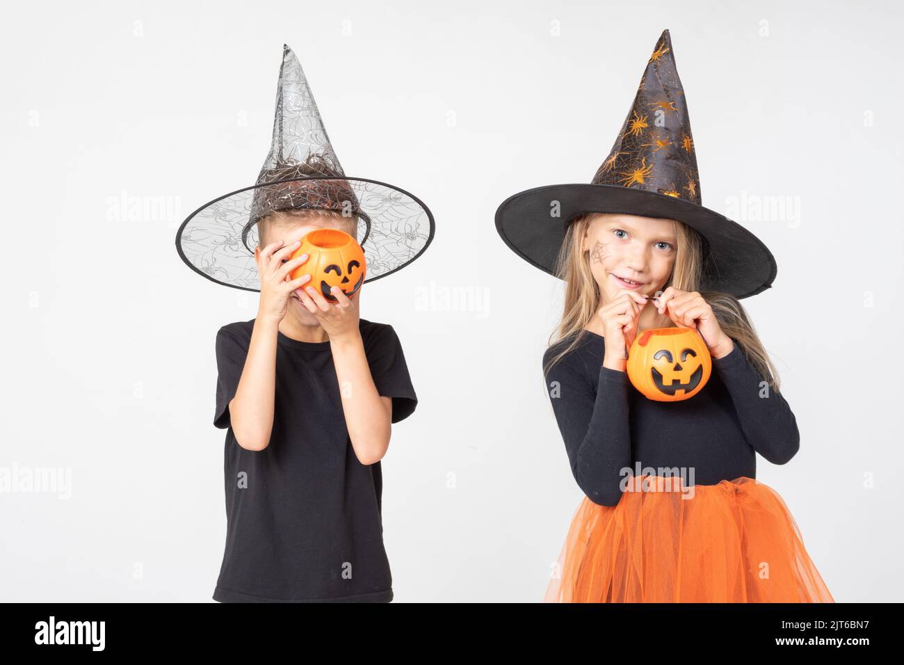 Halloween Für Kinder. Ein schönes, niedliches Mädchen in einem Hexenkostüm und ein Junge, der Körbe in Form von Jacks Laterne hält. Kind hat Spaß an Halloween Trick Stockfoto