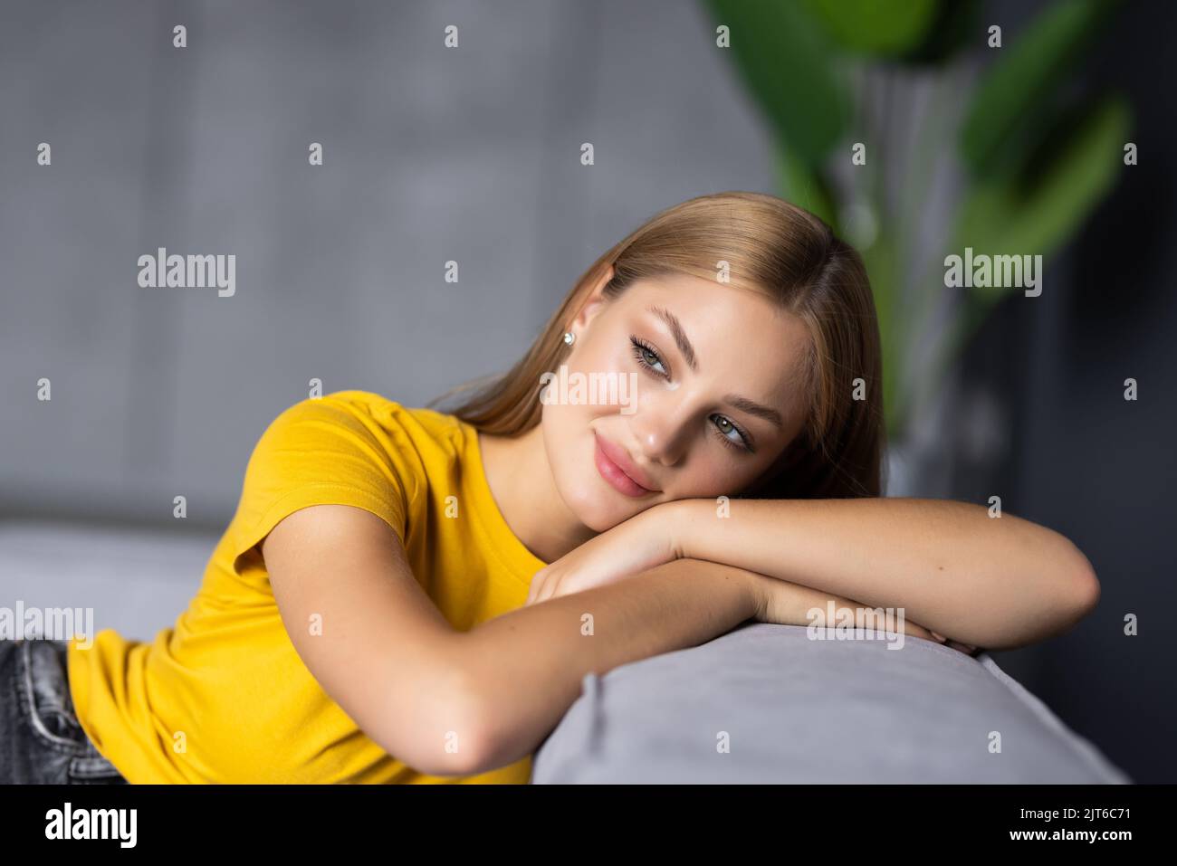 In voller Länge Foto von charmanten schönen attraktiven jungen Frau sitzen Sofa halten Hand Kopf gute Laune drinnen Wohnung Stockfoto