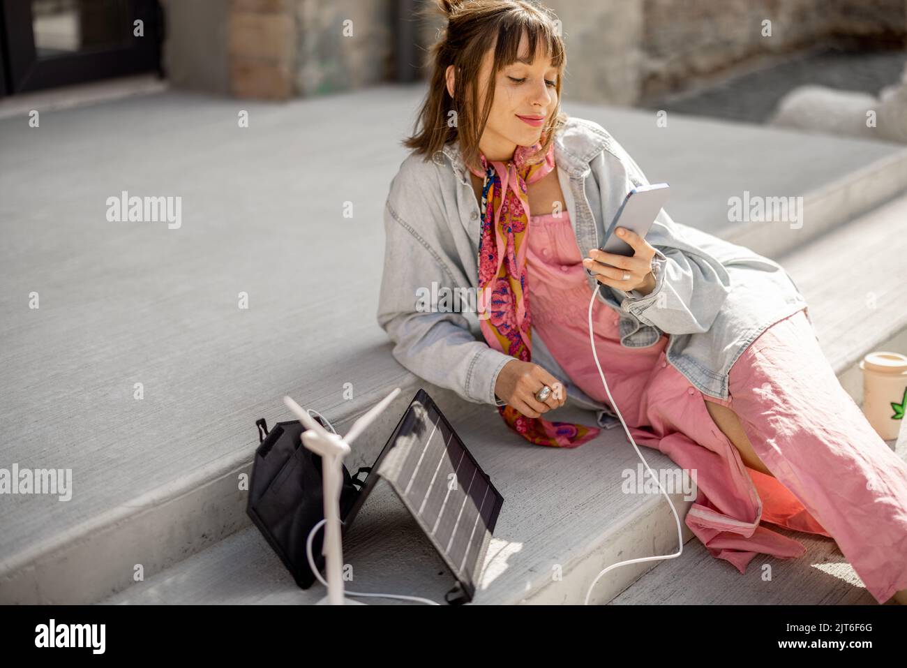 Frau Laden Telefon von einem tragbaren Solarpanel Stockfoto